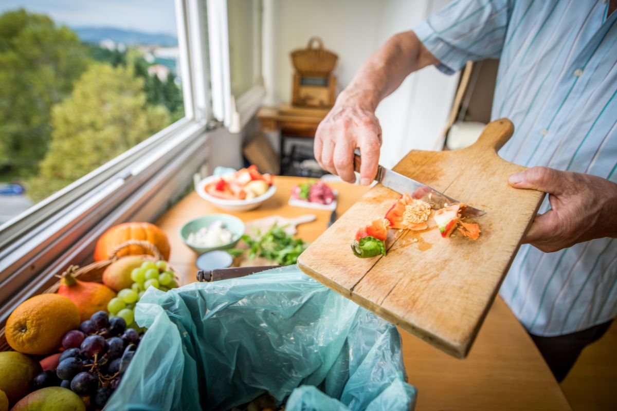 Un homme met les déchets alimentaires dans une poubelle.